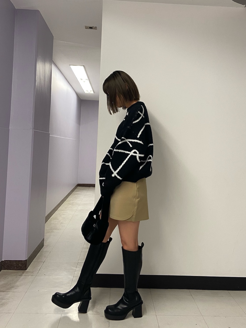 ブラック系のニット/セーター、ベージュ系のスカート、ブラック系のブーツを着用したレディースの秋コーディネートの3枚目の写真