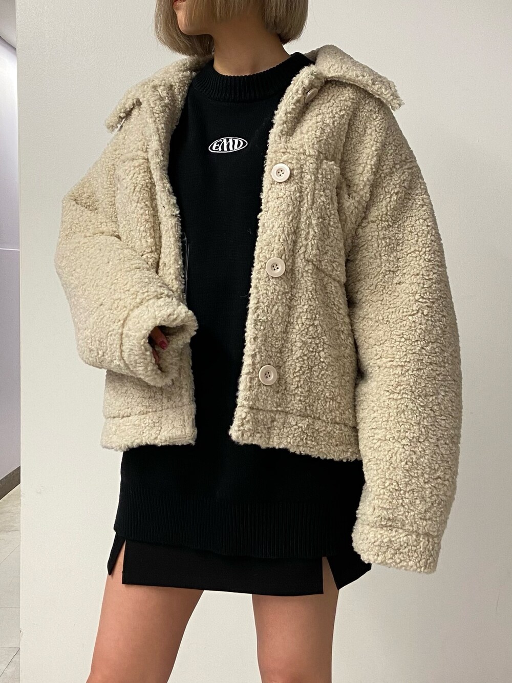 ブラック系のニット/セーター、ホワイト系のブルゾン、ブラック系のスカートを着用したレディースの冬コーディネートの5枚目の写真