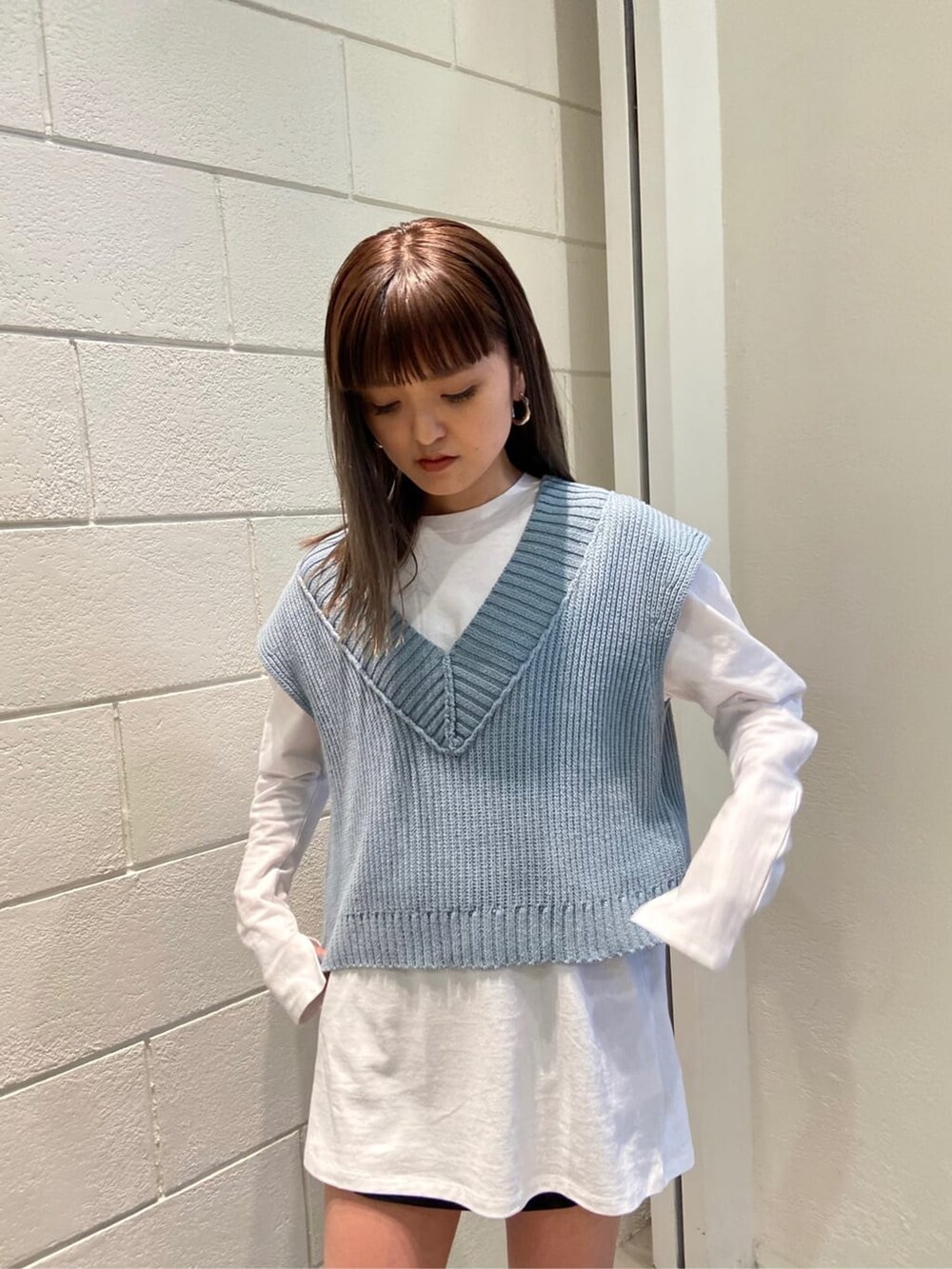 ブラック系のスカート、ブラック系のブーツ、ブルー系のベストを着用したレディースの春コーディネートの3枚目の写真