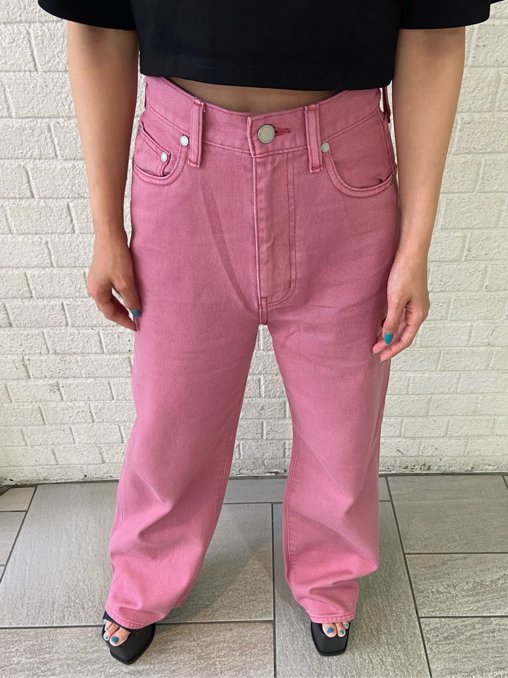 ピンク系のデニムパンツ、ブラック系のサンダル、ブラック系のTシャツ/カットソーを着用したレディースの夏コーディネートの6枚目の写真