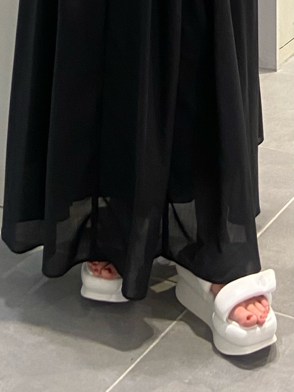 ホワイト系のサンダル、ブラック系のワンピース、ブラック系のキャミソールを着用したレディースの春コーディネートの4枚目の写真