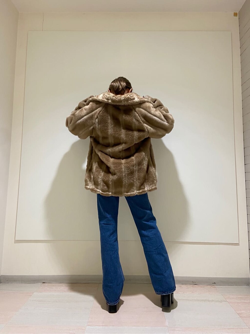 ブルー系のデニムパンツ、ブラック系のブーツ、ベージュ系のその他アウターを着用したレディースの冬コーディネートの4枚目の写真