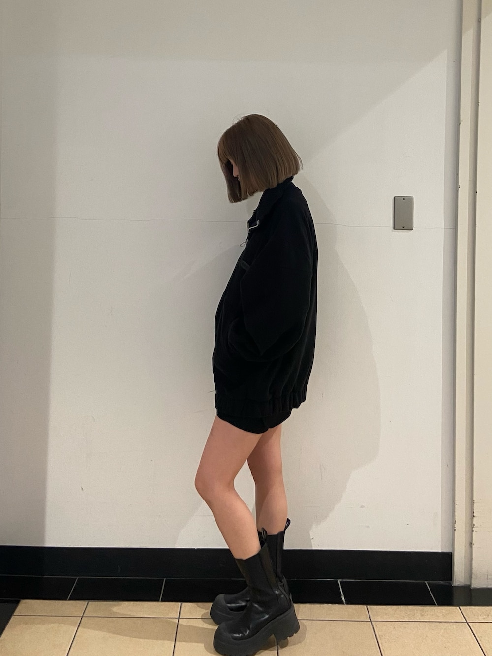 ブラック系のブルゾン、ブラック系のスカート、ブラック系のブーツを着用したレディースの秋コーディネートの2枚目の写真