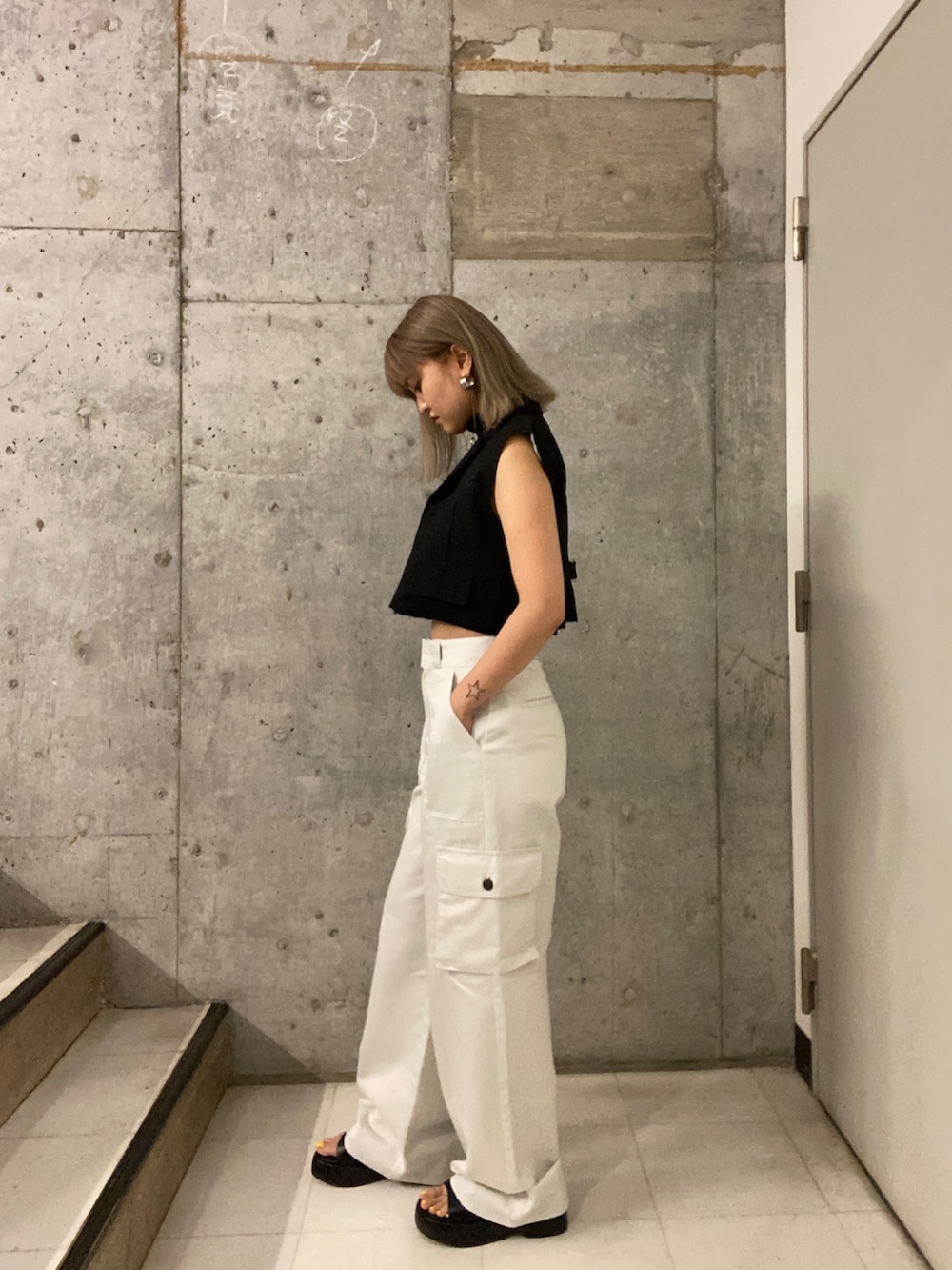 ブラック系のタンクトップ、ホワイト系のカーゴパンツ、ブラック系のサンダルを着用したレディースの夏コーディネートの2枚目の写真