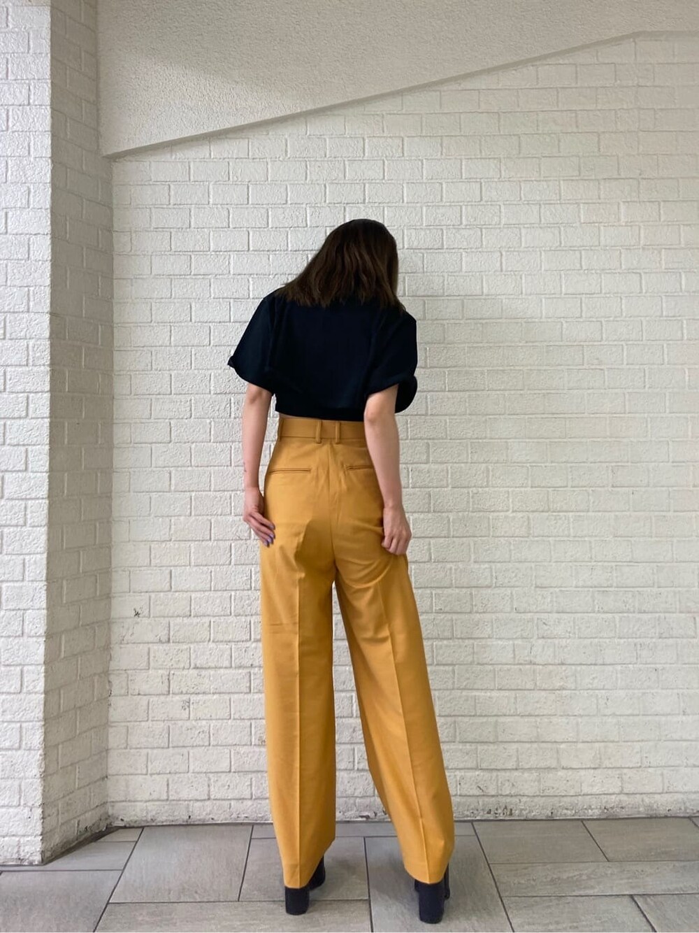 ブラック系のサンダル、オレンジ系のその他パンツ、ブラック系のTシャツ/カットソーを着用したレディースの春コーディネートの3枚目の写真