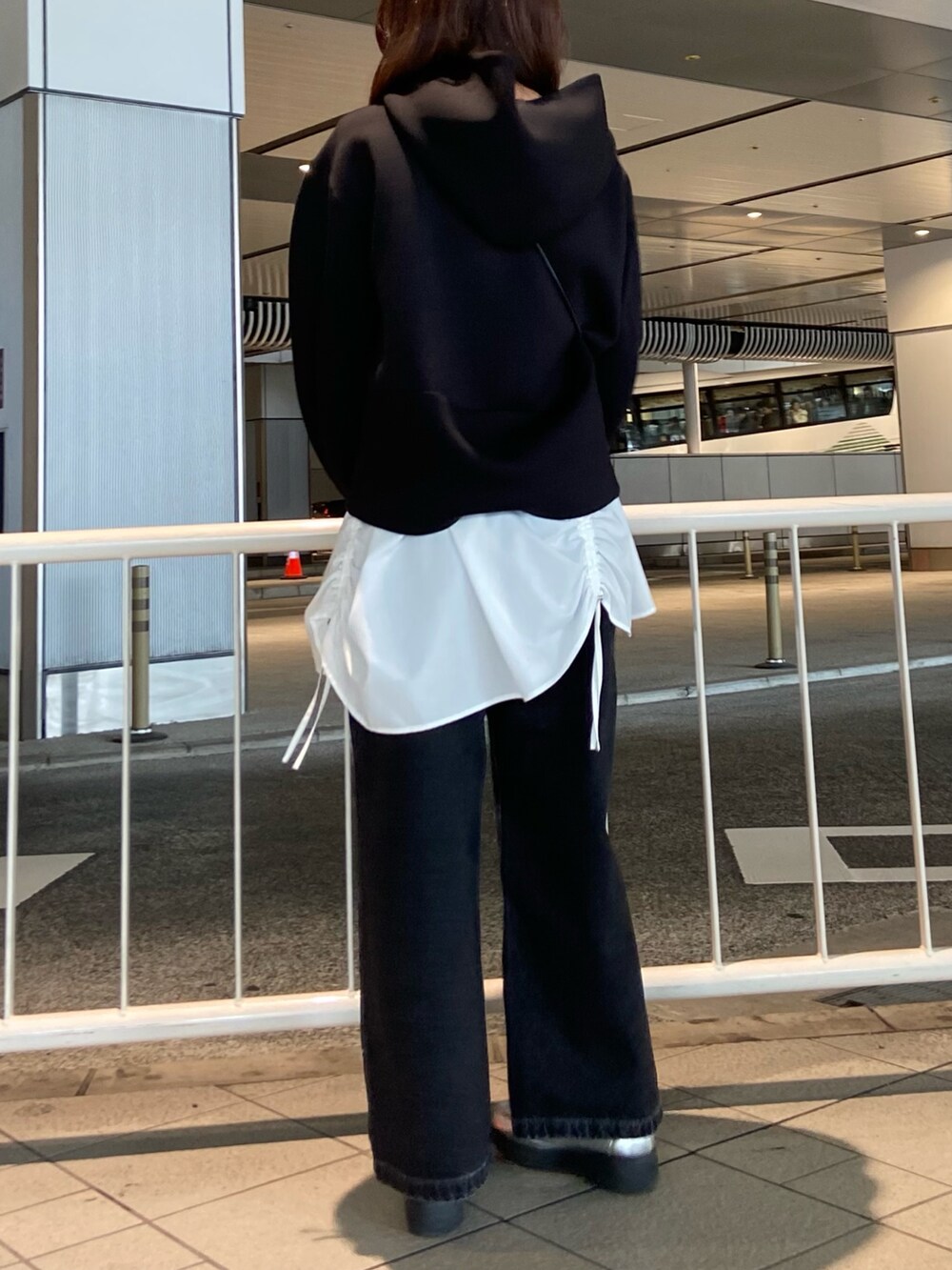 ブラック系のパーカー、ブラック系のデニムパンツ、シルバー系のローファーを着用したレディースの冬コーディネートの4枚目の写真