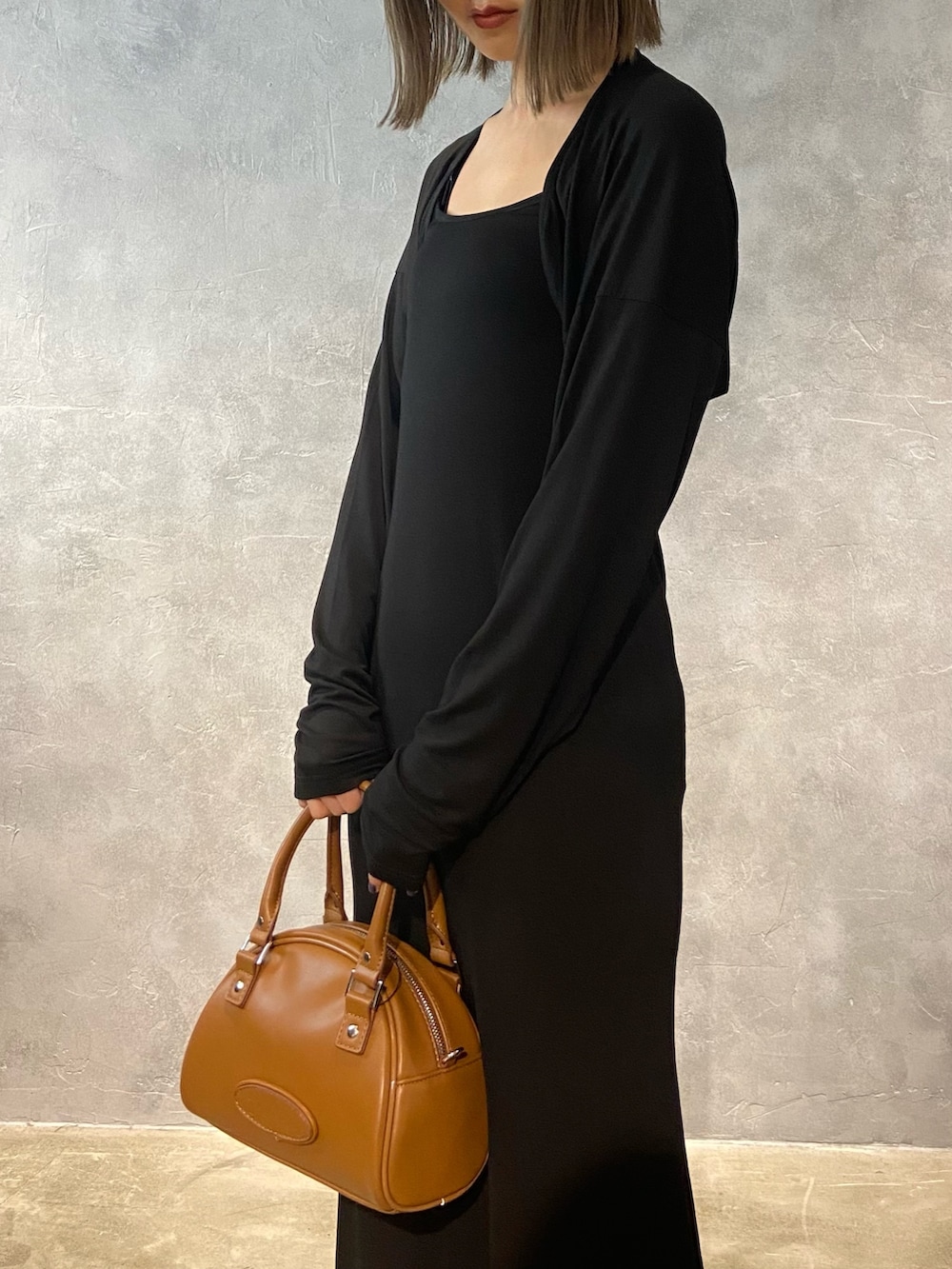 ブラック系のワンピース、ブラック系のハンドバッグ、ホワイト系のサンダルを着用したレディースの春コーディネートの6枚目の写真