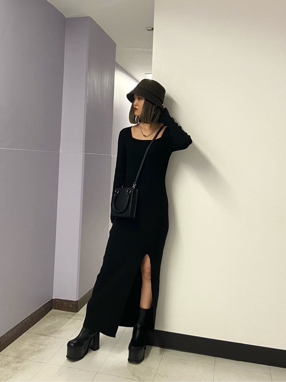 ブラック系のワンピース、ブラック系のブーツ、ブラック系のハンドバッグを着用したレディースの秋コーディネートの2枚目の写真