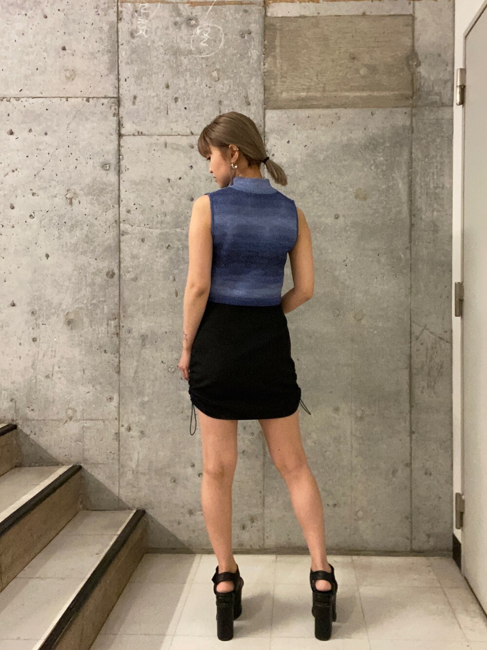 ブルー系のタンクトップ、ブラック系のスカート、ブラック系のサンダルを着用したレディースの春コーディネートの3枚目の写真