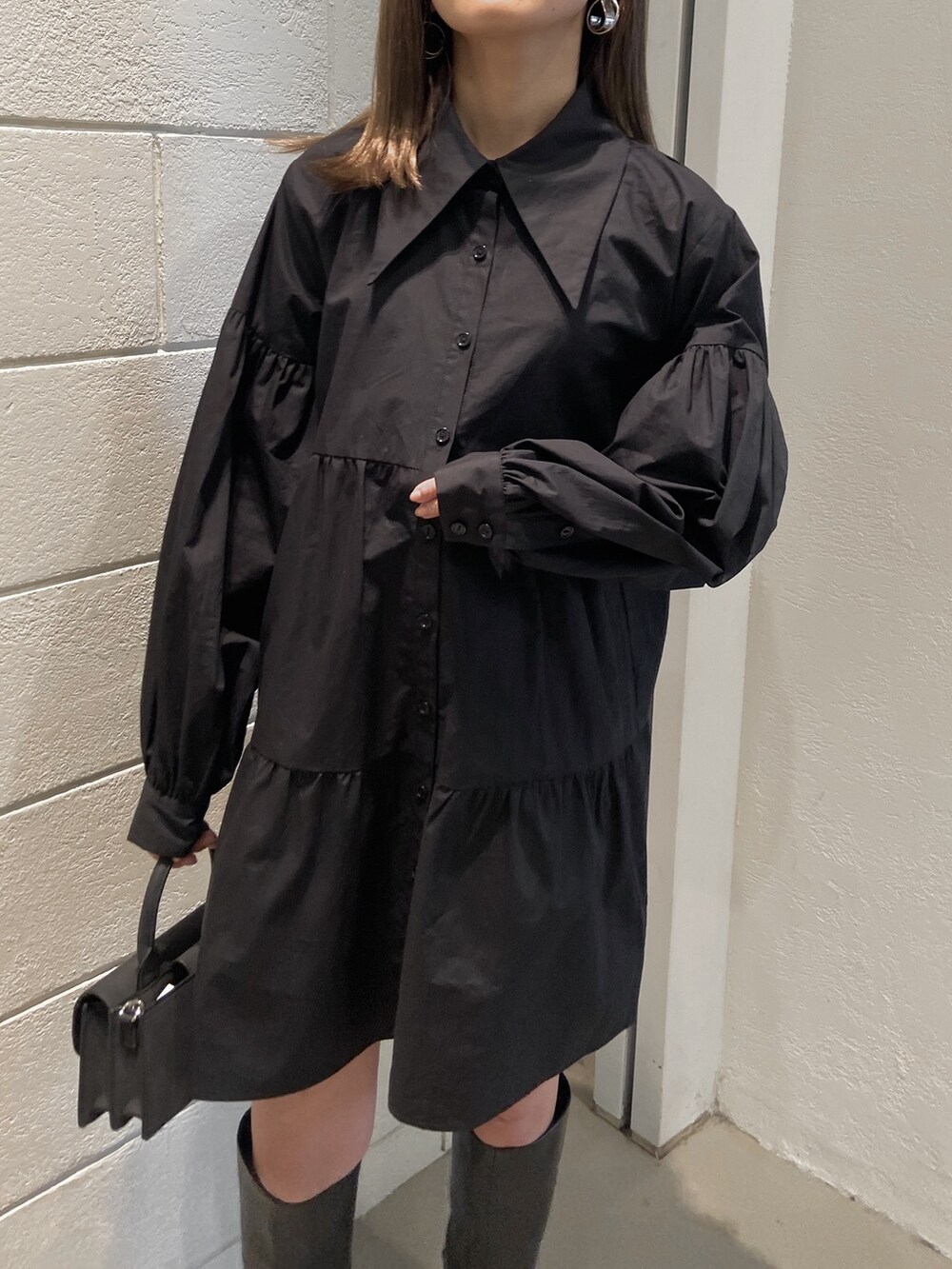 ブラック系のシャツワンピース、ブラック系のブーツ、ブラック系のハンドバッグを着用したレディースの冬コーディネートの3枚目の写真