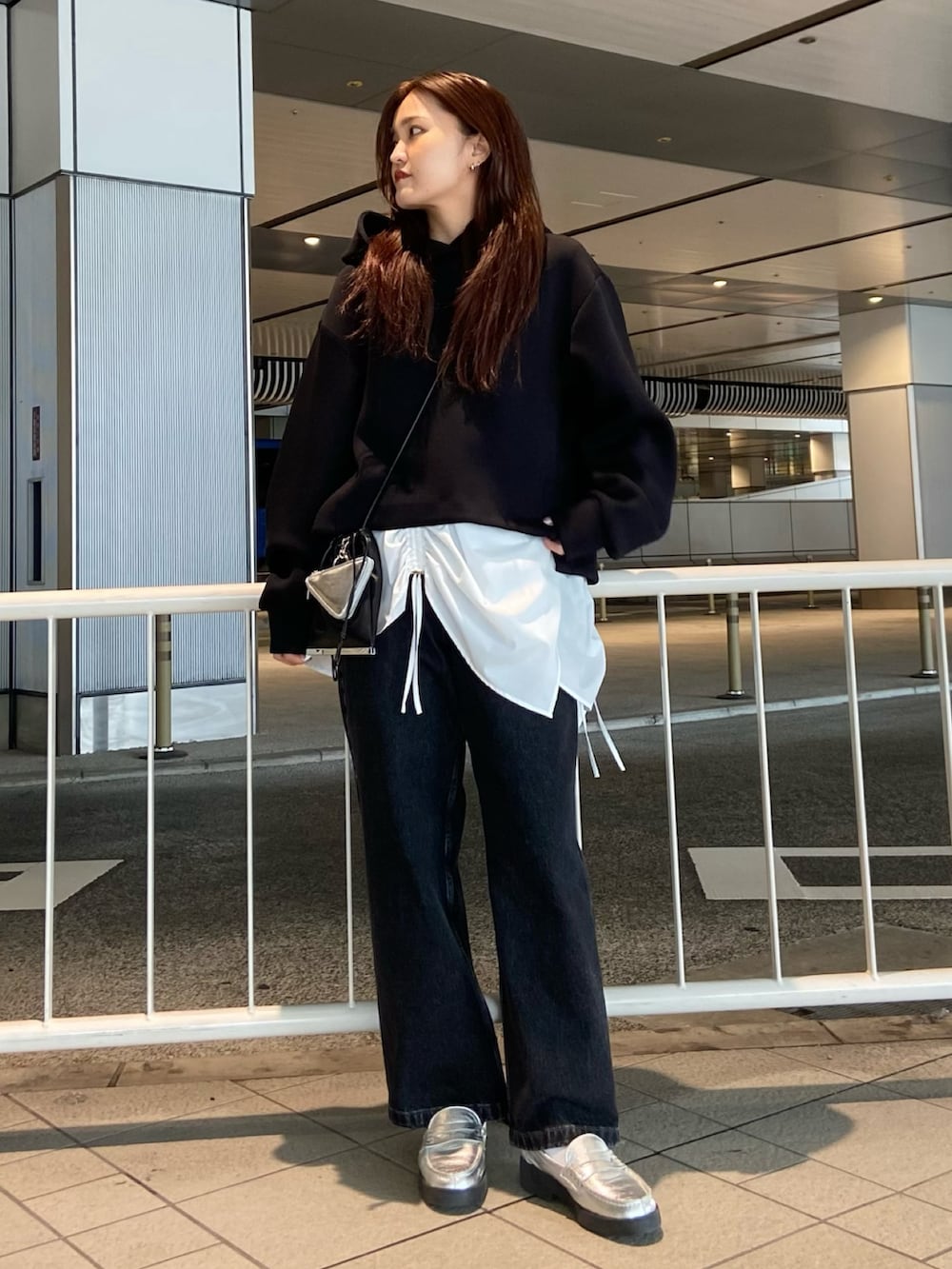 ブラック系のパーカー、ブラック系のデニムパンツ、シルバー系のローファーを着用したレディースの冬コーディネートの2枚目の写真