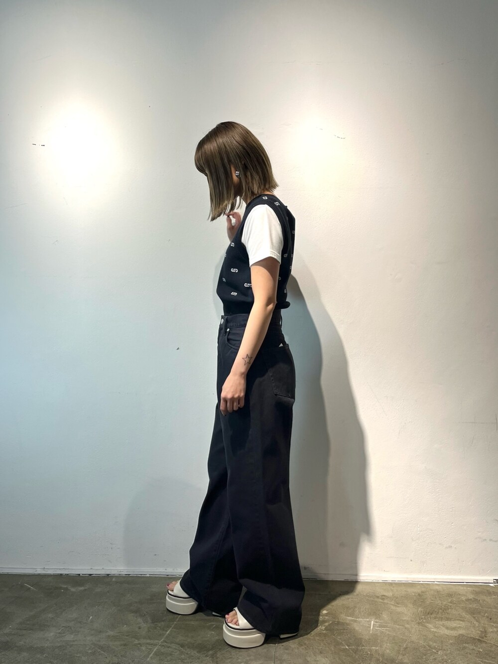 ホワイト系のTシャツ/カットソー、ブラック系のデニムパンツ、ホワイト系のサンダルを着用したレディースの春コーディネートの3枚目の写真