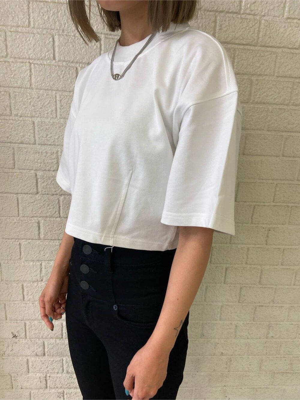 ブラック系のデニムパンツ、ブラック系のサンダル、ホワイト系のTシャツ/カットソーを着用したレディースの夏コーディネートの6枚目の写真