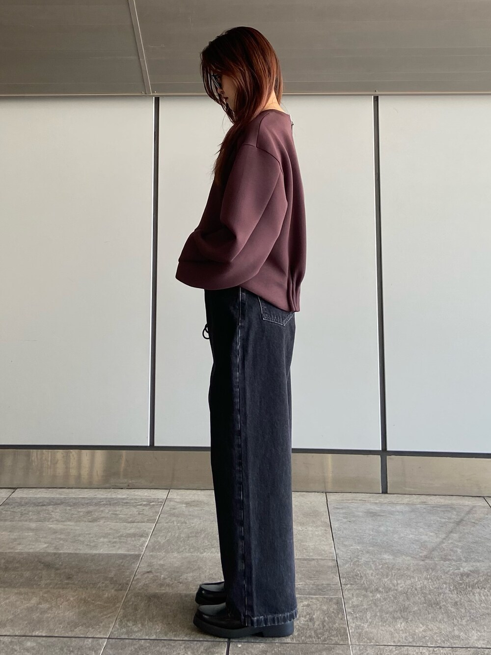 ブラウン系のスウェット、ブラック系のデニムパンツ、ブラック系のローファーを着用したレディースの夏コーディネートの3枚目の写真