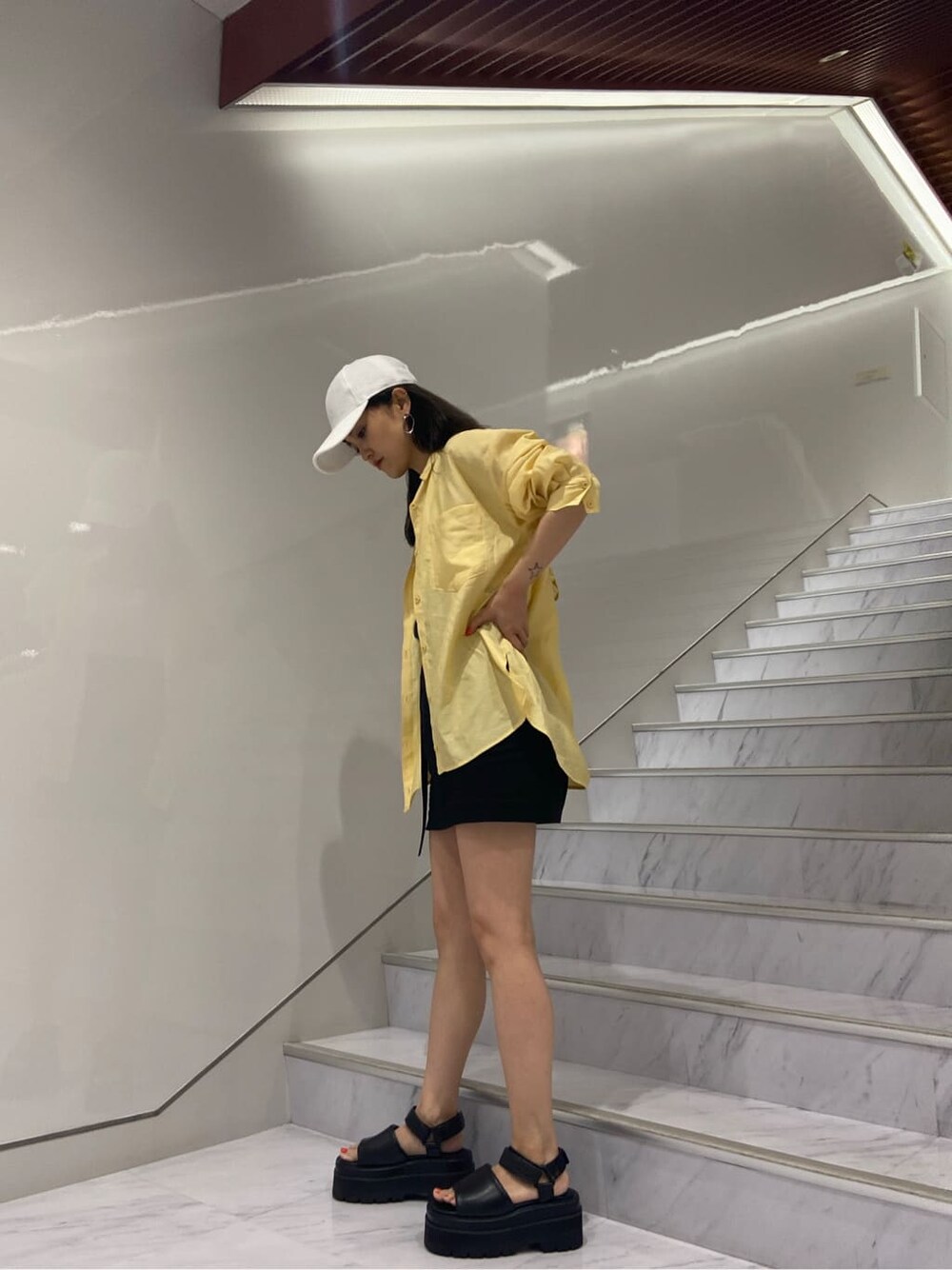 ホワイト系のタンクトップ、ブラック系のサンダル、ブラック系のスカートを着用したレディースの夏コーディネートの4枚目の写真