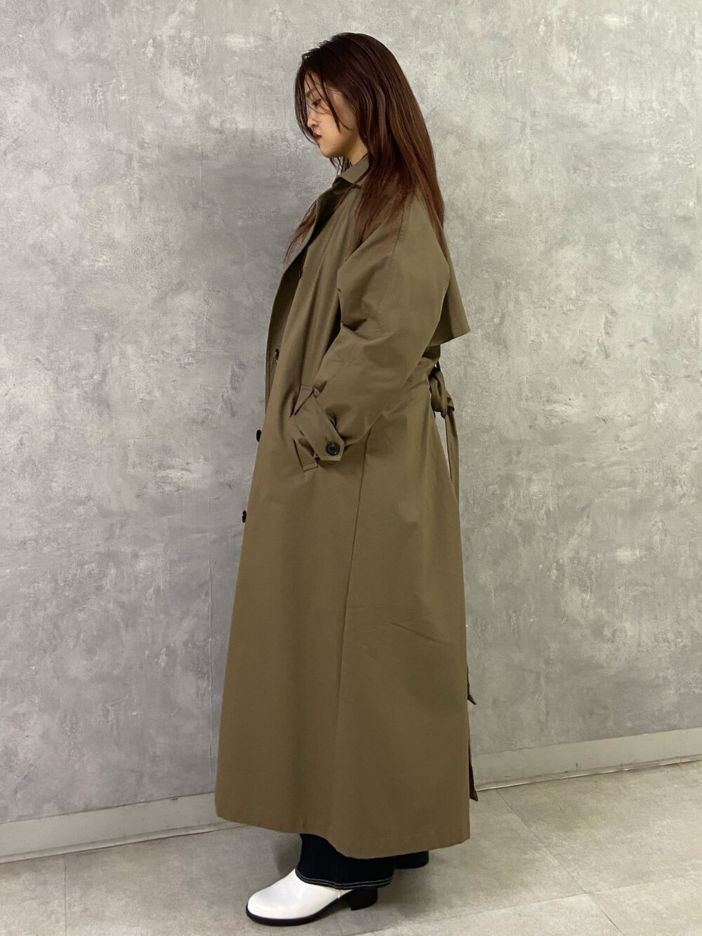 ブラウン系のトレンチコート、ブラック系のニット/セーター、ブルー系のデニムパンツを着用したレディースの秋コーディネートの3枚目の写真