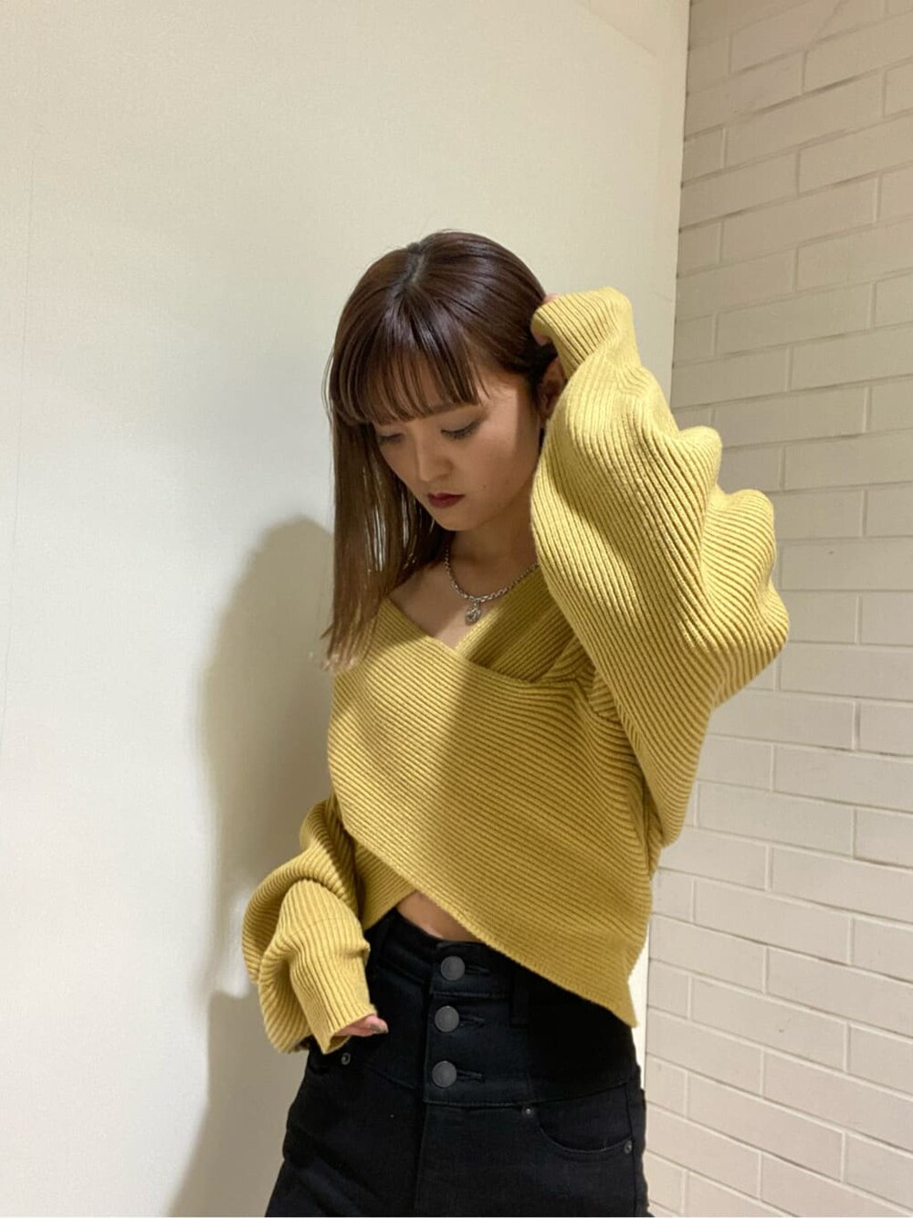 ブラック系のデニムパンツ、ブラック系のブーツ、イエロー系のニット/セーターを着用したレディースの冬コーディネートの4枚目の写真