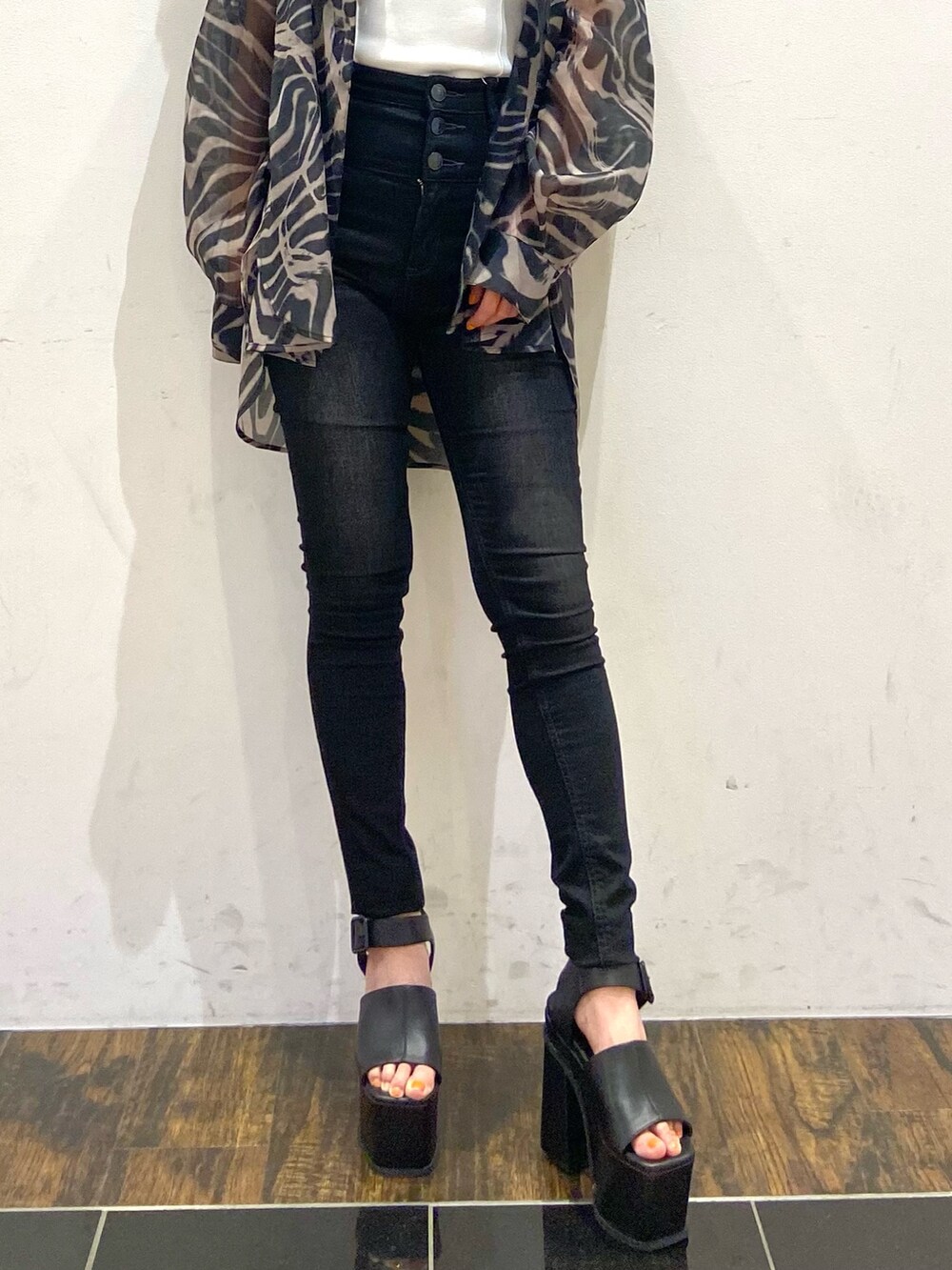 ブラック系のデニムパンツ、ブラック系のサンダル、ホワイト系のタンクトップを着用したレディースの春コーディネートの2枚目の写真