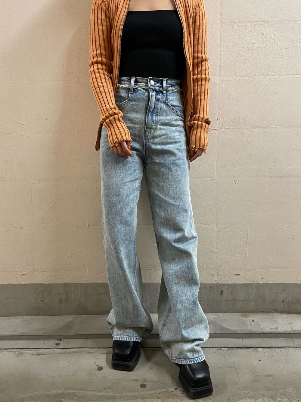 オレンジ系のニット/セーター、ブラック系のキャミソール、ブルー系のデニムパンツを着用したレディースの春コーディネートの5枚目の写真