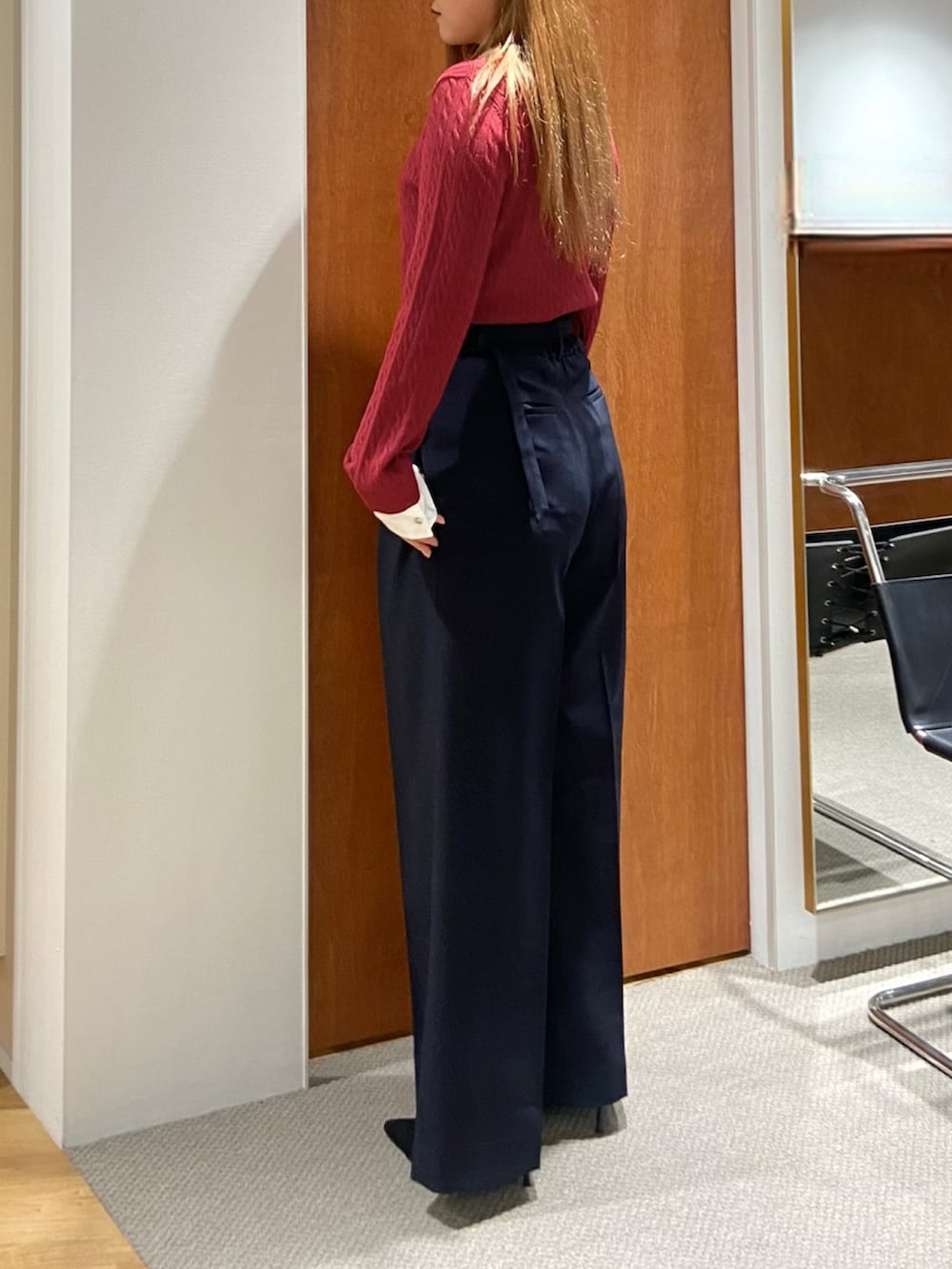 レッド系のニット/セーター、ブルー系のスラックスを着用したレディースの秋コーディネートの3枚目の写真