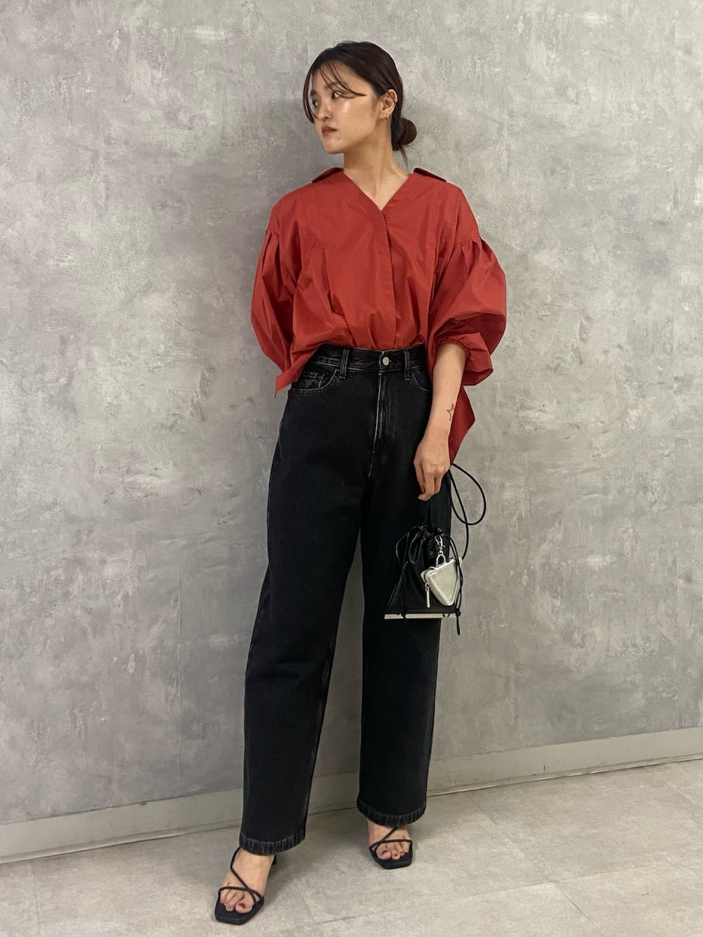 オレンジ系のシャツ/ブラウス、ブラック系のサンダル、ブラック系のデニムパンツを着用したレディースの夏コーディネートの2枚目の写真