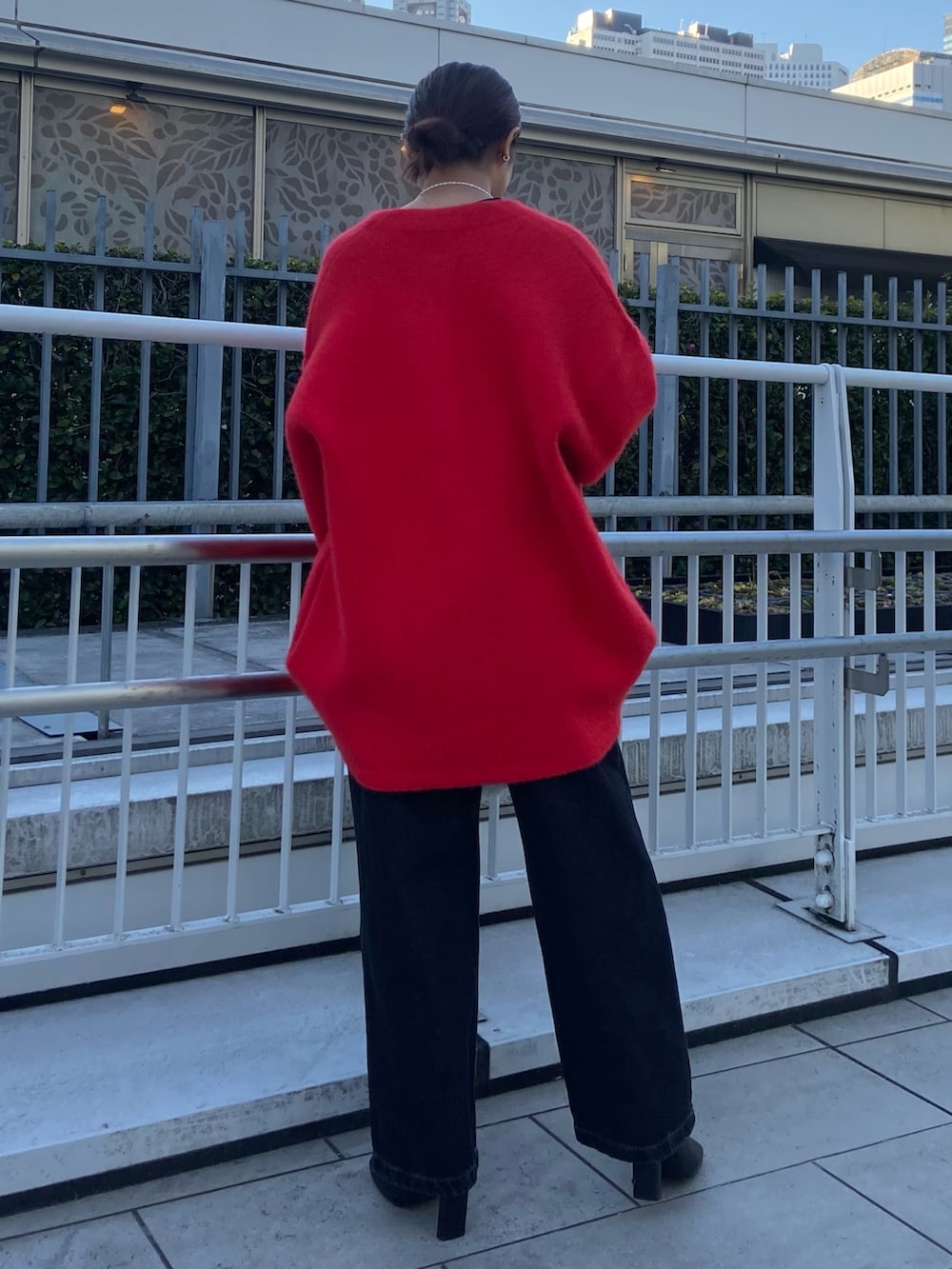 レッド系のカーディガン/ボレロ、ブラック系のデニムパンツ、ブラック系のブーツを着用したレディースの冬コーディネートの3枚目の写真