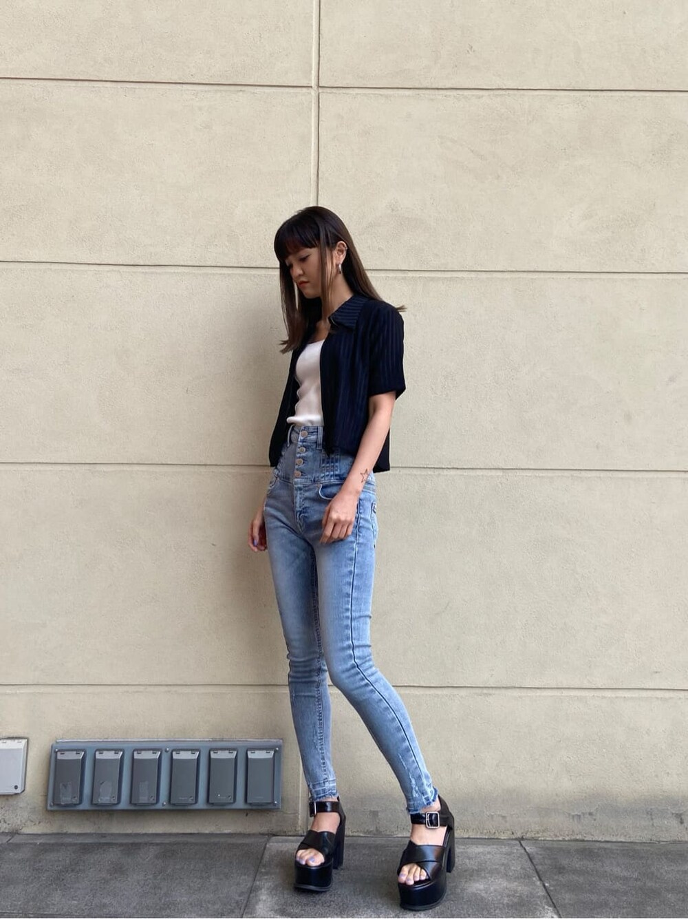 ブルー系のデニムパンツ、ホワイト系のタンクトップ、ブラック系のサンダルを着用したレディースの春コーディネートの3枚目の写真