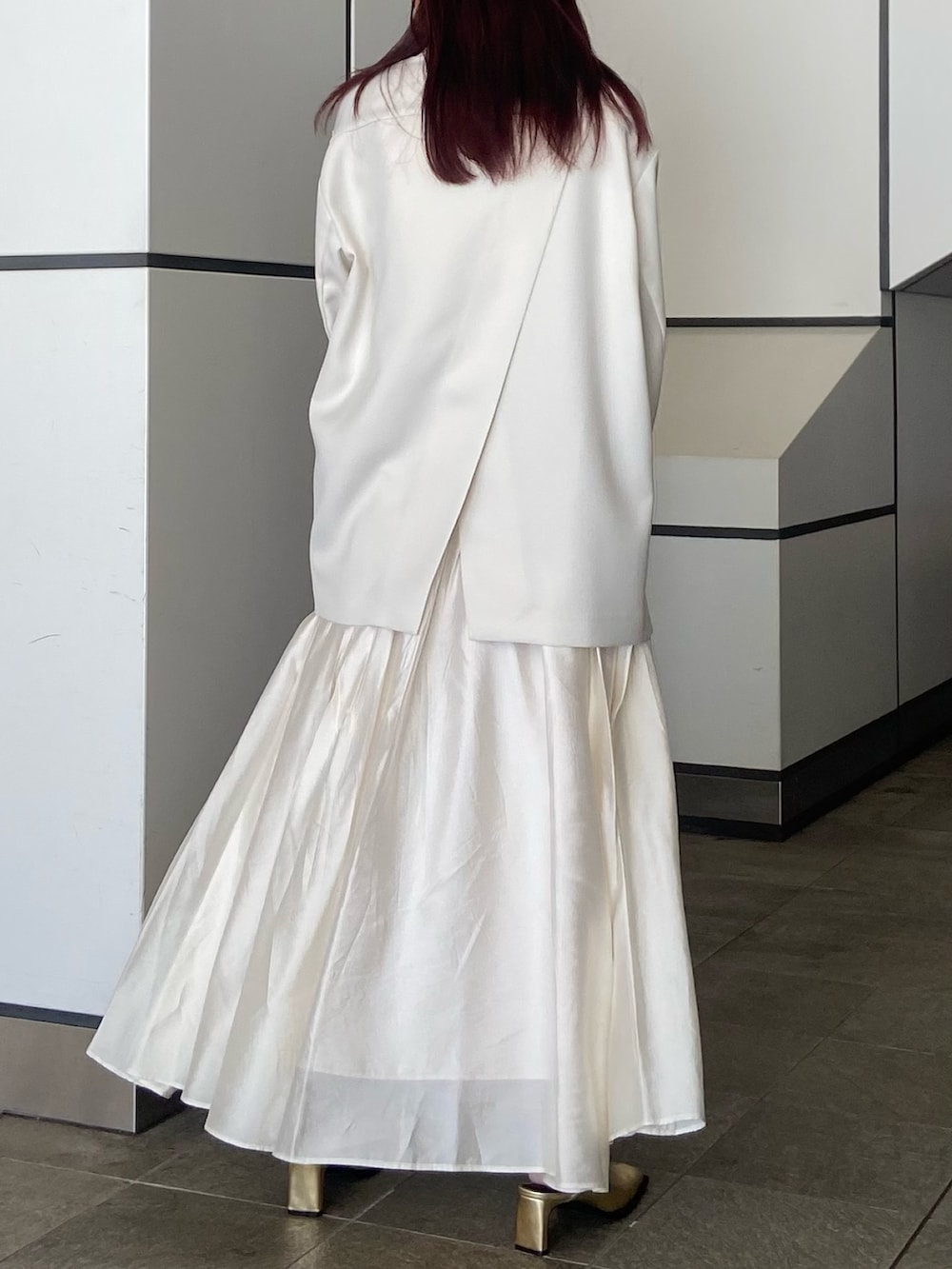 ホワイト系のテーラードジャケット、ホワイト系のスカート、ゴールド系のサンダルを着用したレディースの冬コーディネートの3枚目の写真