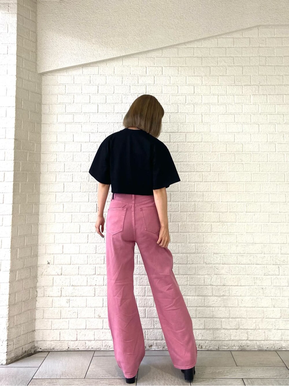 ピンク系のデニムパンツ、ブラック系のサンダル、ブラック系のTシャツ/カットソーを着用したレディースの夏コーディネートの2枚目の写真