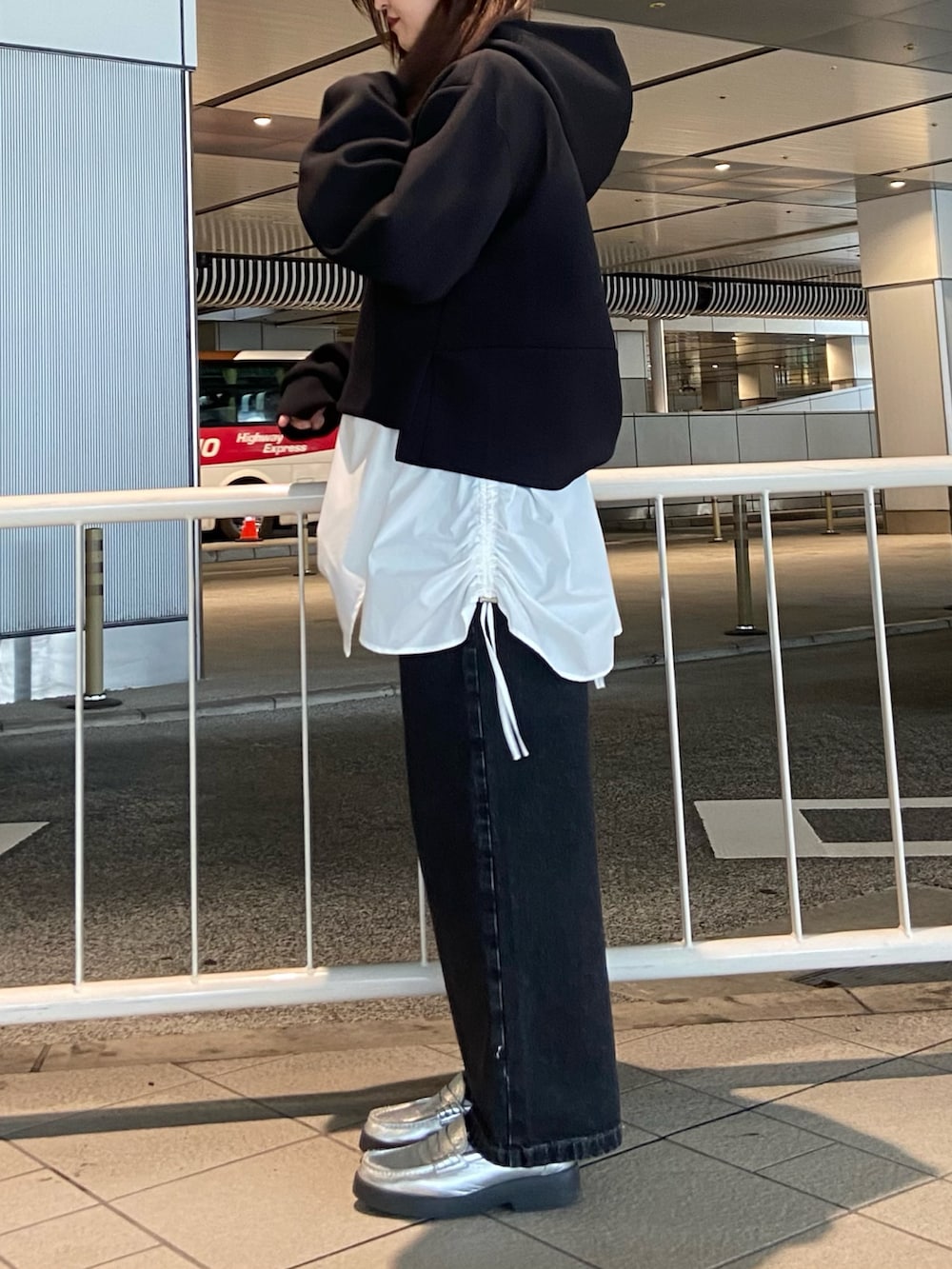 ブラック系のパーカー、ブラック系のデニムパンツ、シルバー系のローファーを着用したレディースの冬コーディネートの3枚目の写真