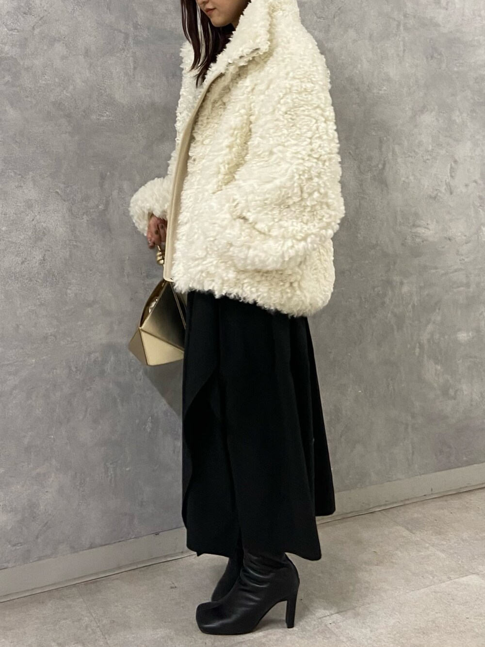 ホワイト系のブルゾン、ブラック系のワンピース、ブラック系のブーツを着用したレディースの冬コーディネートの2枚目の写真