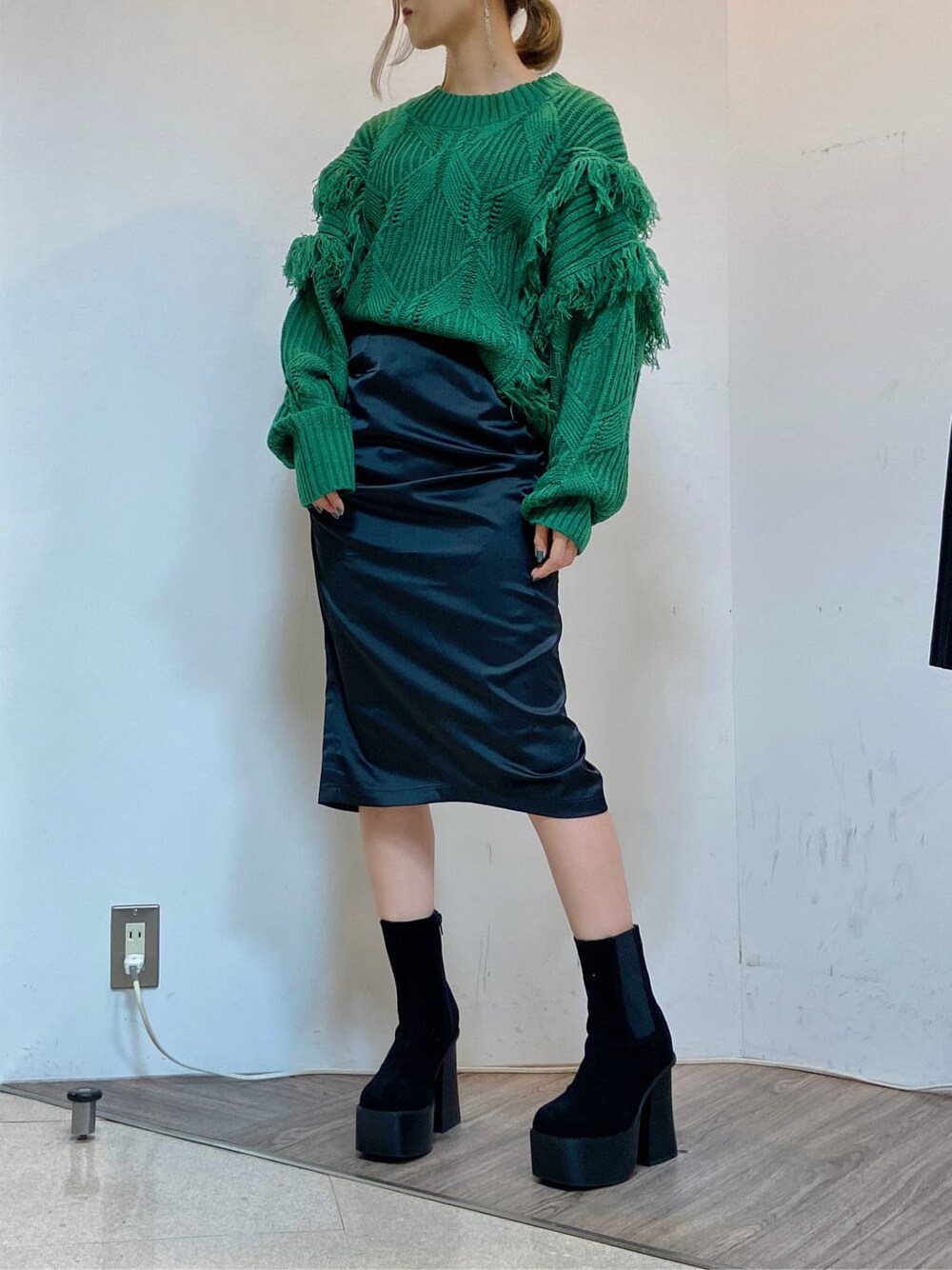ブラック系のスカート、ブラック系のブーツ、グリーン系のニット/セーターを着用したレディースの秋コーディネートの4枚目の写真