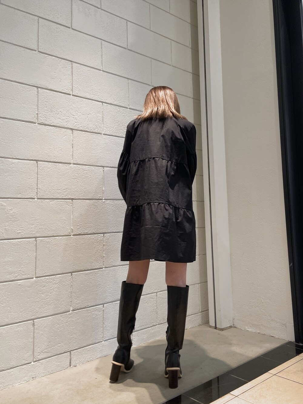 ブラック系のシャツワンピース、ブラック系のブーツ、ブラック系のハンドバッグを着用したレディースの冬コーディネートの5枚目の写真