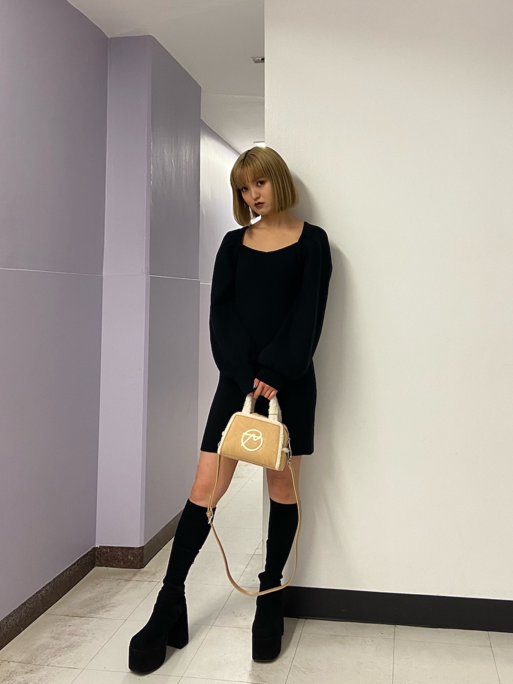 ブラック系のワンピース、ベージュ系のハンドバッグ、ブラック系のブーツを着用したレディースの冬コーディネートの2枚目の写真