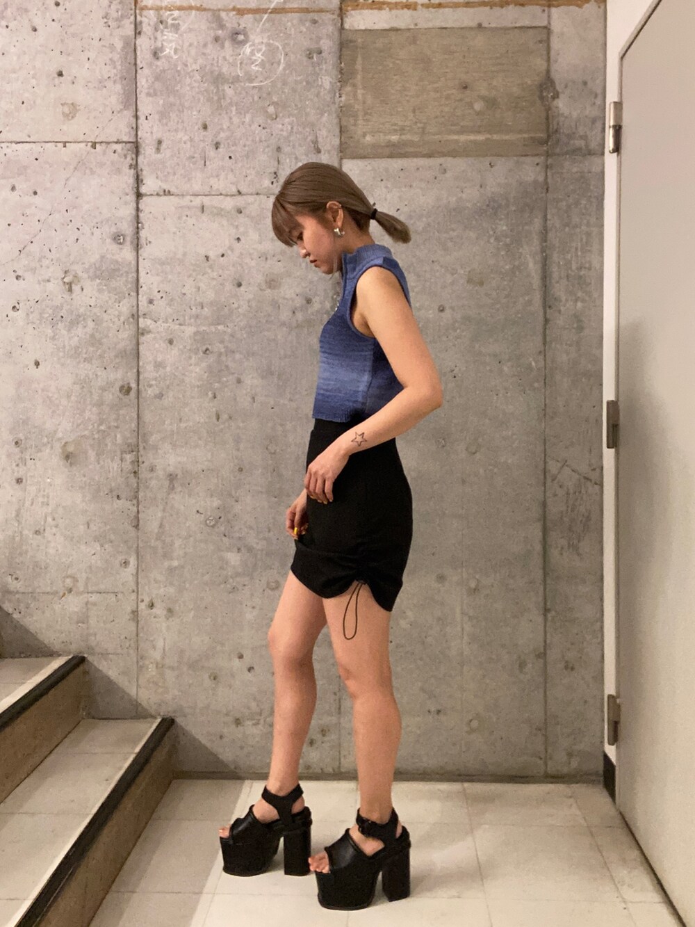 ブルー系のタンクトップ、ブラック系のスカート、ブラック系のサンダルを着用したレディースの春コーディネートの2枚目の写真