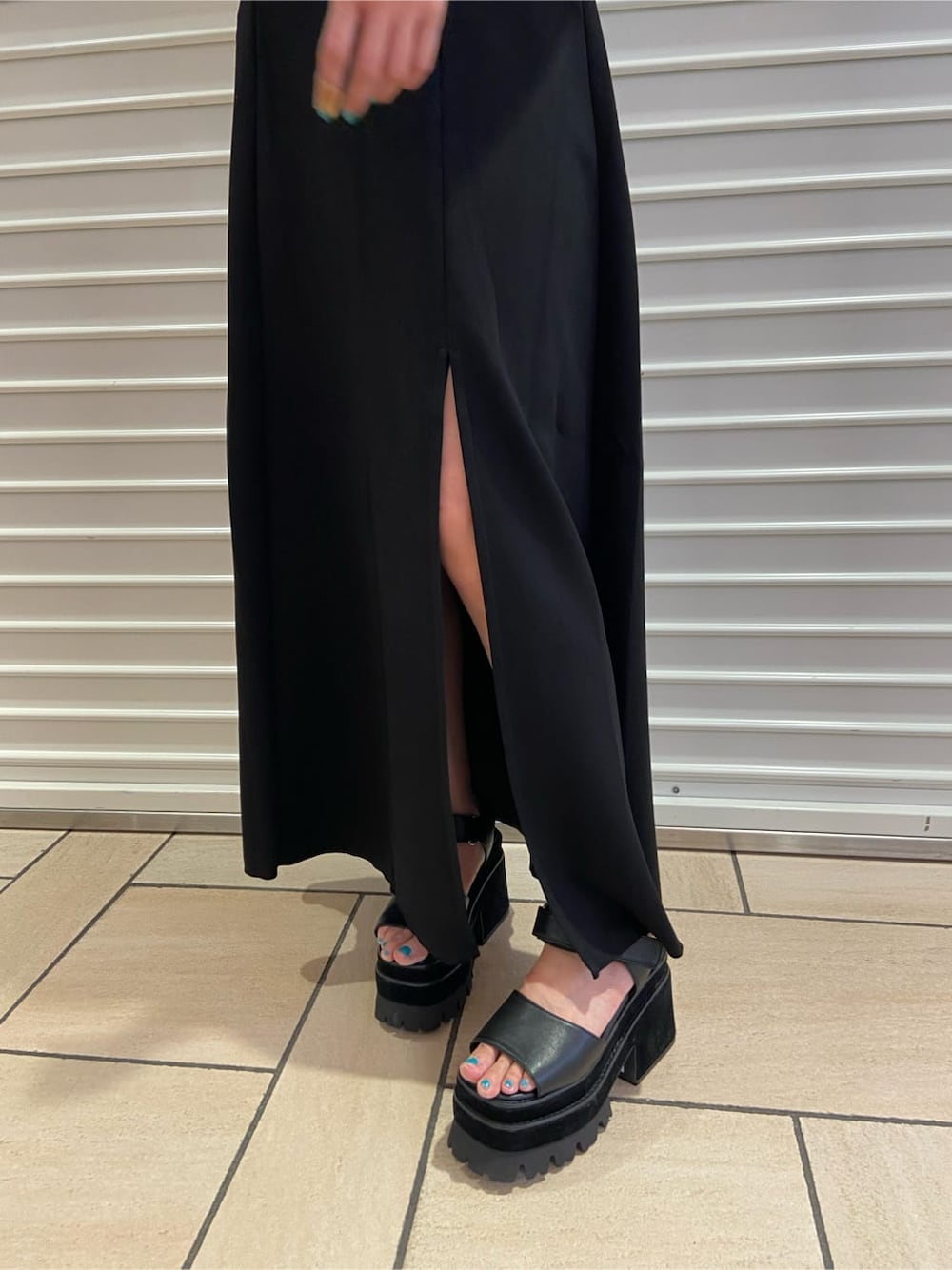 ブラック系のスカート、ブラック系のサンダル、グレー系のTシャツ/カットソーを着用したレディースの夏コーディネートの7枚目の写真