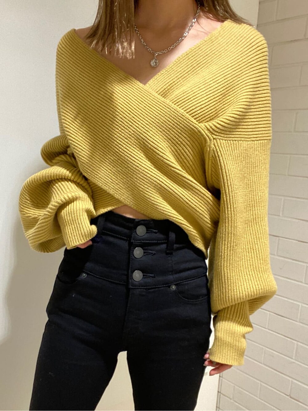 ブラック系のデニムパンツ、ブラック系のブーツ、イエロー系のニット/セーターを着用したレディースの冬コーディネートの3枚目の写真