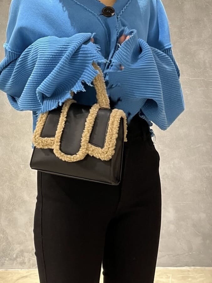 ブラック系のデニムパンツ、ブラック系のハンドバッグ、ブルー系のカーディガン/ボレロを着用したレディースの秋コーディネートの6枚目の写真