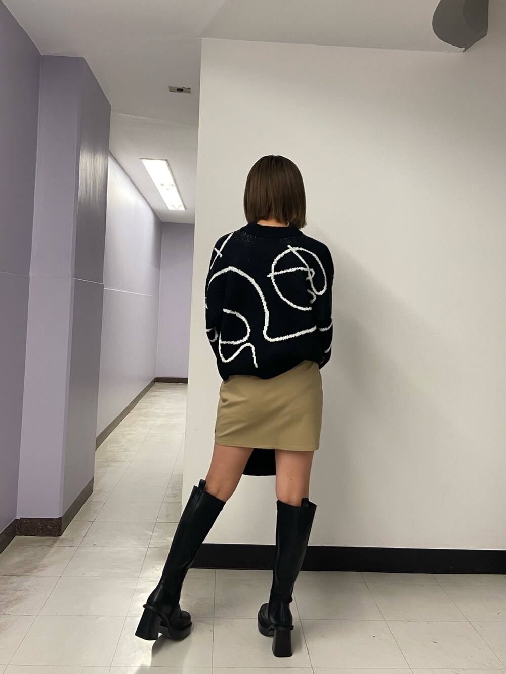 ブラック系のニット/セーター、ベージュ系のスカート、ブラック系のブーツを着用したレディースの秋コーディネートの4枚目の写真