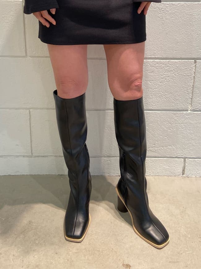 ブラック系のワンピース、ベージュ系のトレンチコート、ブラック系のブーツを着用したレディースの冬コーディネートの7枚目の写真