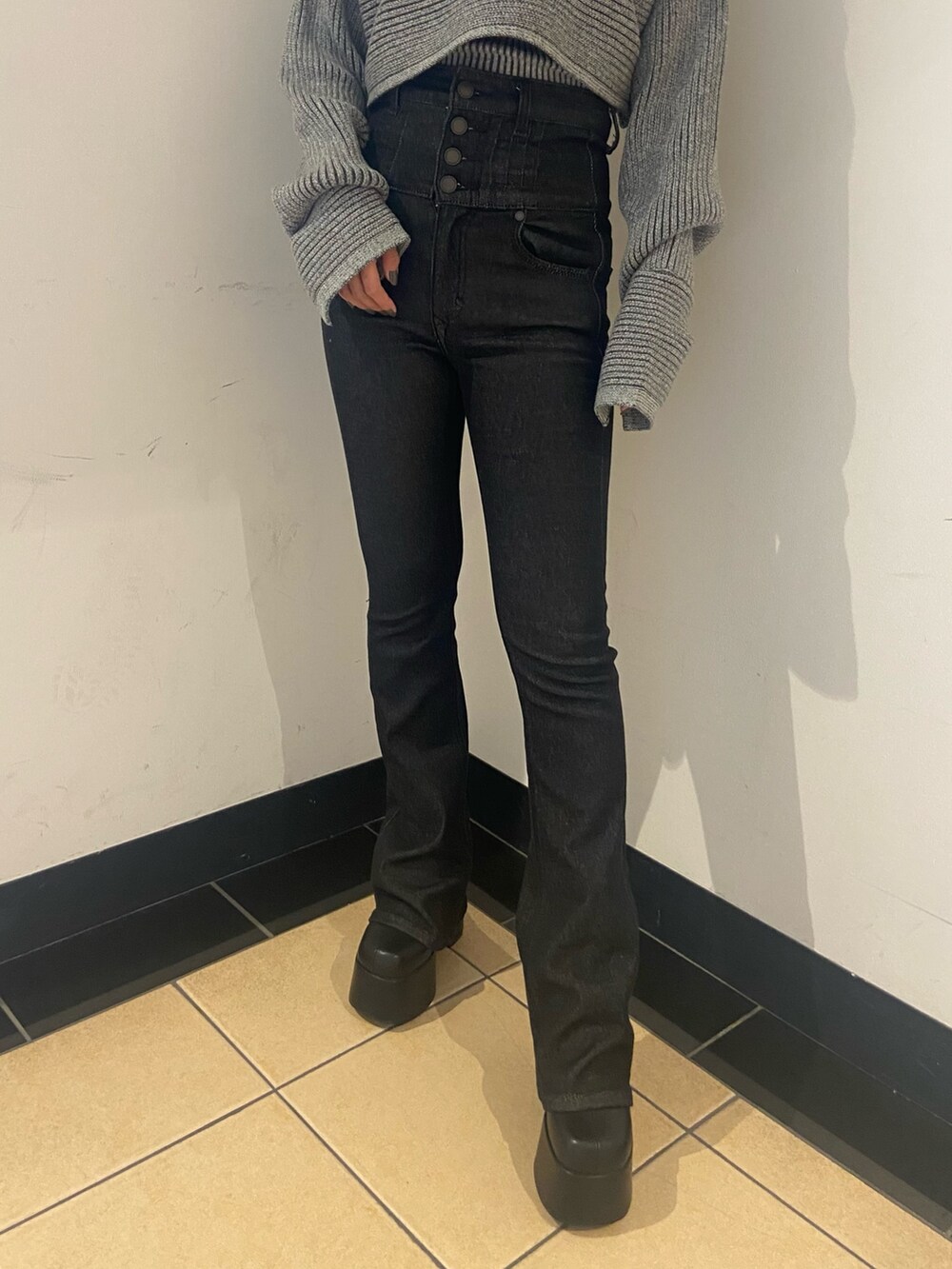 グレー系のニット/セーター、ブラック系のデニムパンツ、ブラック系のブーツを着用したレディースの秋コーディネートの5枚目の写真