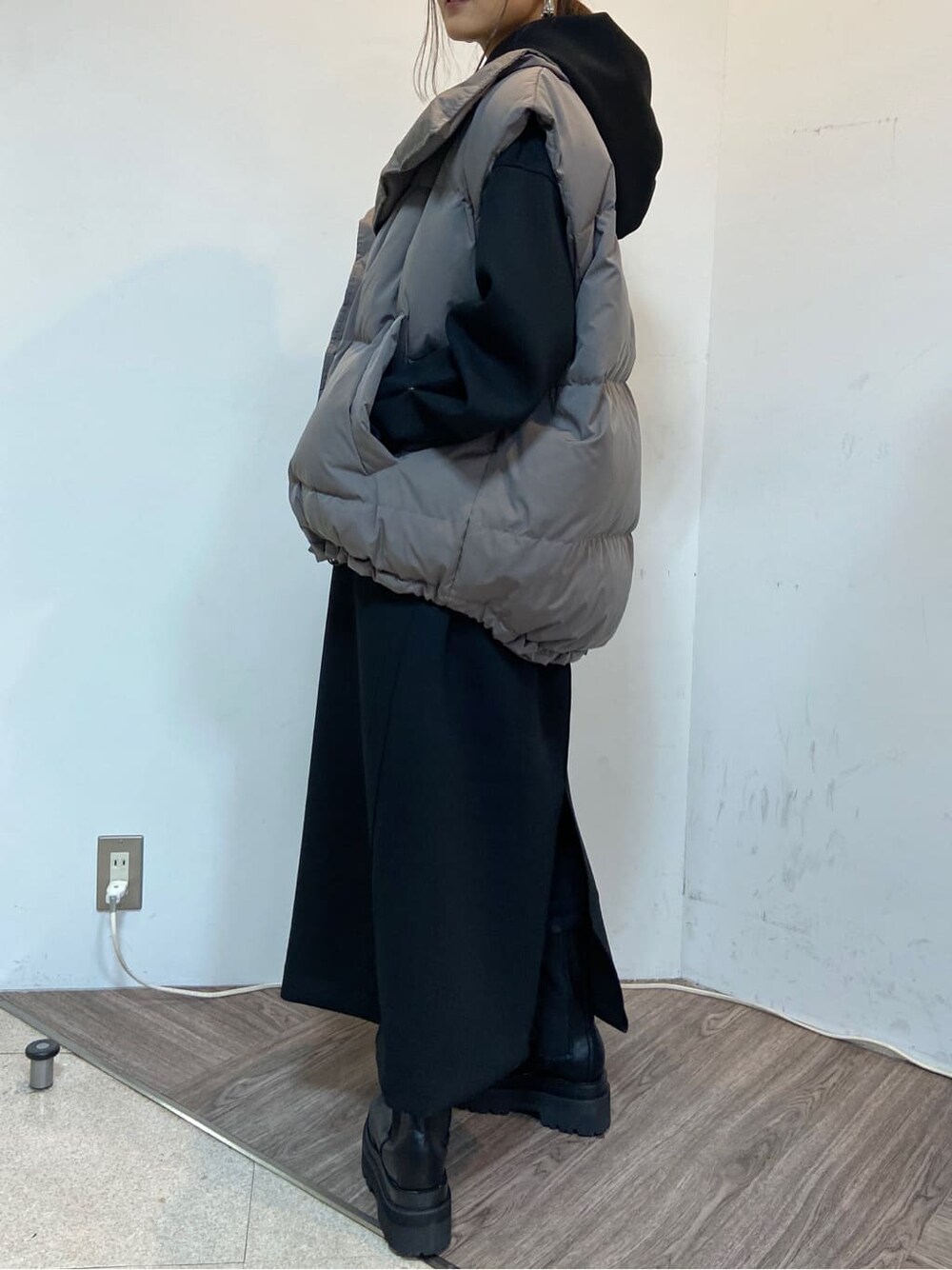 グレー系のダウンベスト、ブラック系のワンピースを着用したレディースの秋コーディネートの5枚目の写真