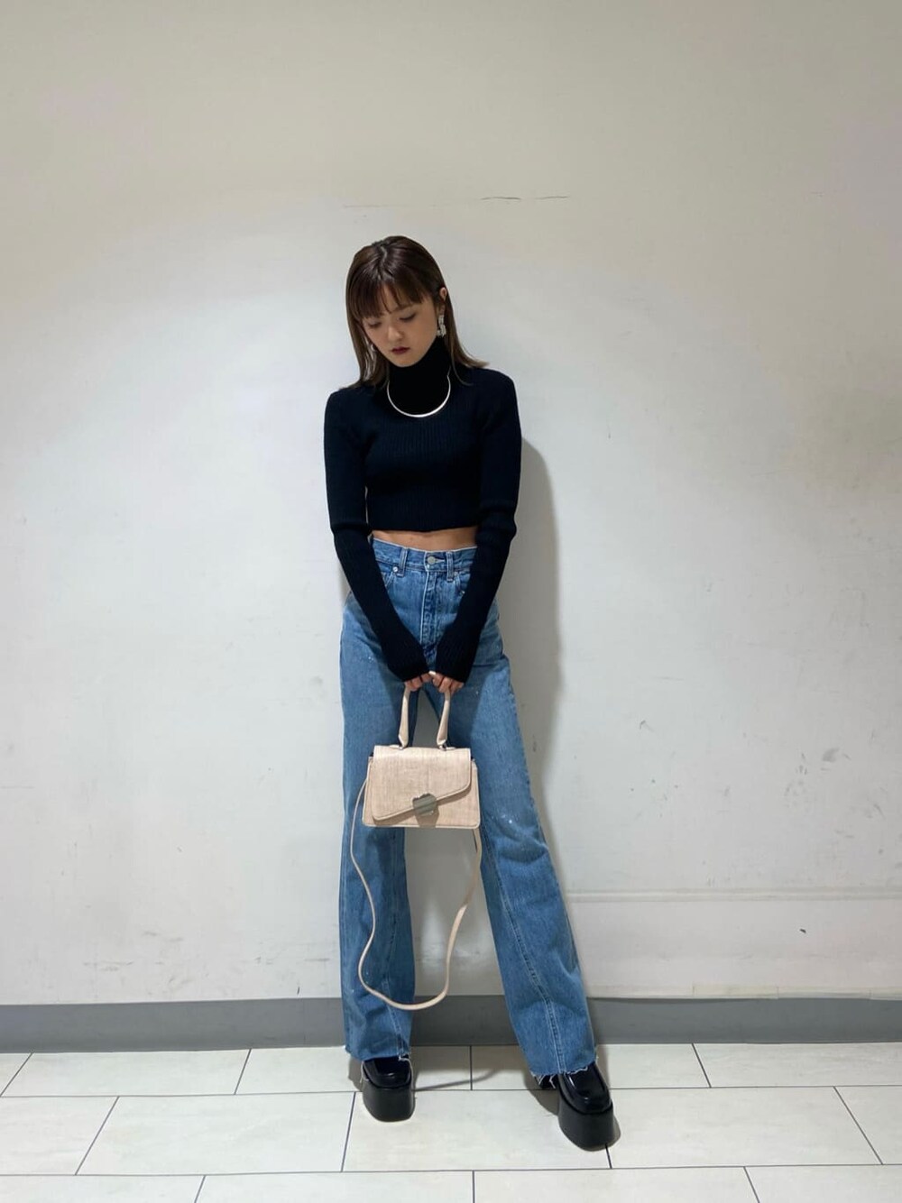 ブラック系のニット/セーター、ブルー系のデニムパンツ、ブラック系のローファーを着用したレディースの冬コーディネートの6枚目の写真