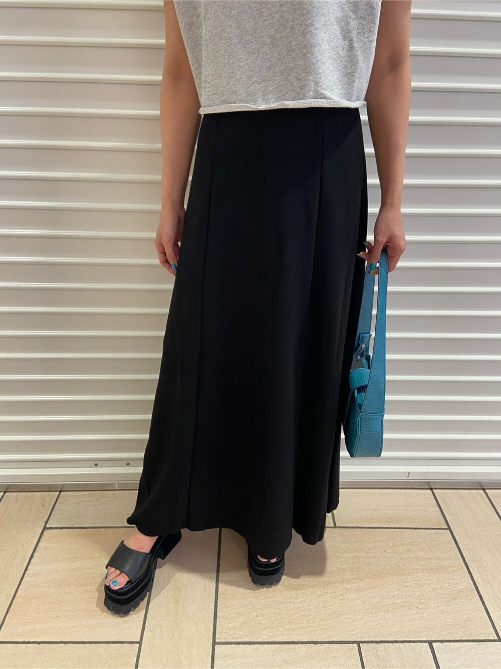 ブラック系のスカート、ブラック系のサンダル、グレー系のTシャツ/カットソーを着用したレディースの夏コーディネートの6枚目の写真