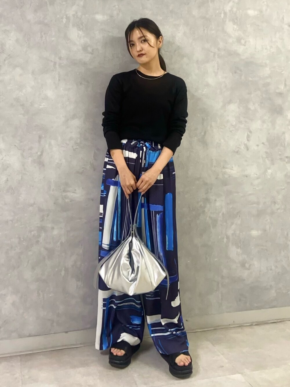 ブラック系のニット/セーター、ブルー系のその他パンツ、シルバー系のショルダーバッグを着用したレディースの秋コーディネートの2枚目の写真