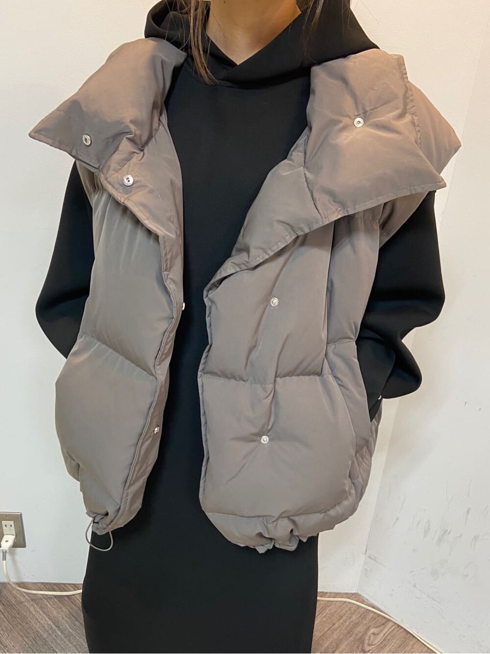 グレー系のダウンベスト、ブラック系のワンピースを着用したレディースの秋コーディネートの2枚目の写真