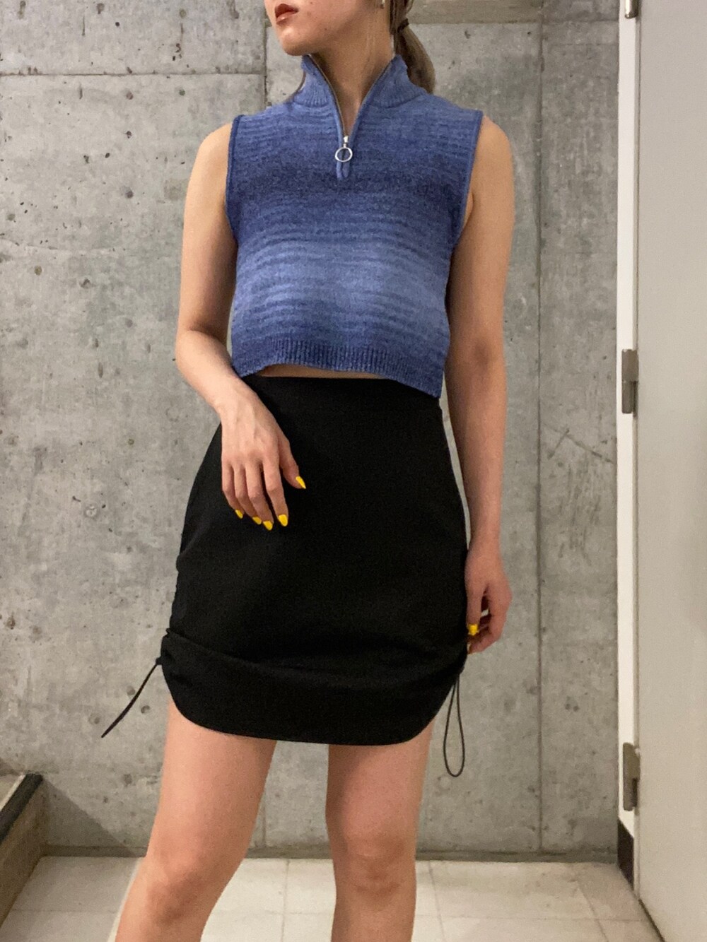 ブルー系のタンクトップ、ブラック系のスカート、ブラック系のサンダルを着用したレディースの春コーディネートの4枚目の写真