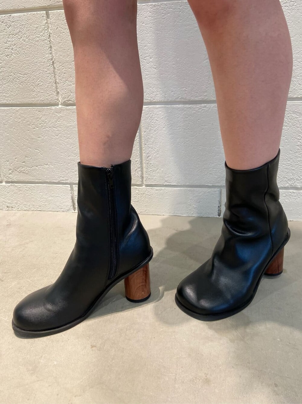 ブラック系のスカート、ブラック系のブーツ、ブルー系のベストを着用したレディースの春コーディネートの7枚目の写真