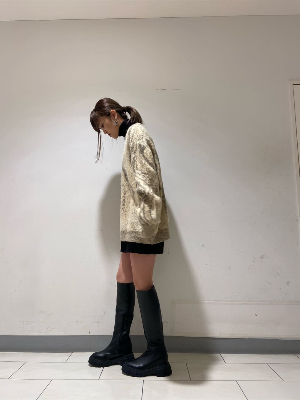 ブラック系のブーツ、ブラック系のスカート、ブラック系のニット/セーターを着用したレディースの冬コーディネートの4枚目の写真