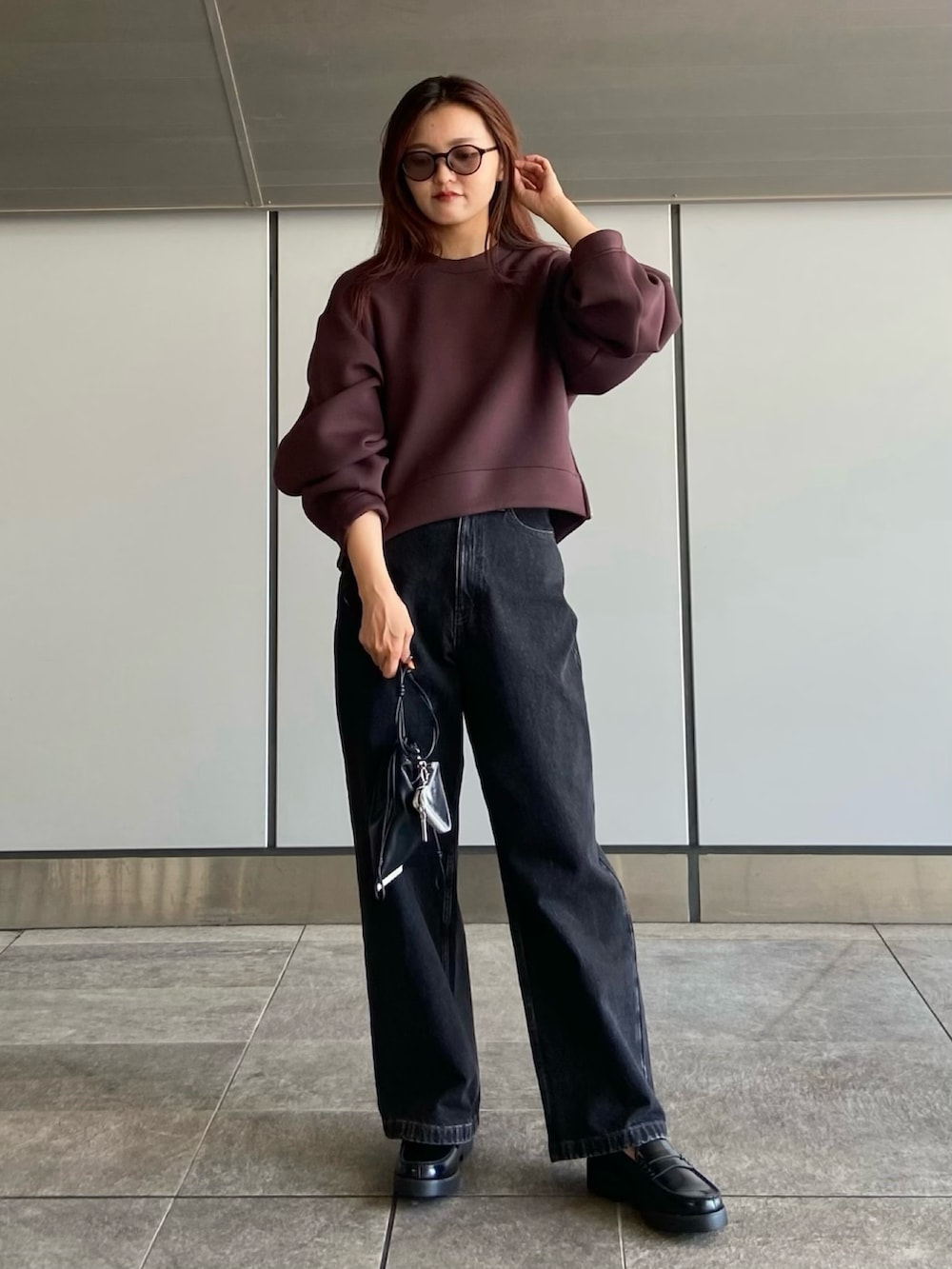 ブラウン系のスウェット、ブラック系のデニムパンツ、ブラック系のローファーを着用したレディースの夏コーディネートの2枚目の写真